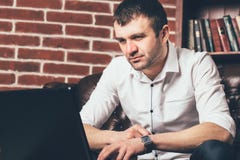 Красивый человек смотрит экран ноутбука на предпосылке шкафа офиса Он одет в деловом костюме в черно-белом co стоковые фото Красивый человек смотрит экран ноутбука на предпосылке шкафа офиса Он одет в деловом костюме в черно-белом co стоковые фото