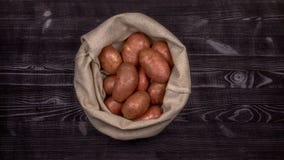Красные сырцовые картошки в сумке на черной деревенской предпосылке д стоковые фотографии rf Красные сырцовые картошки в сумке на черной деревенской предпосылке д стоковые фотографии rf