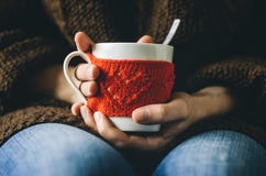 Красный цвет связал шерстяную чашку с картиной сердца в женских руках Стоковые Изображения Красный цвет связал шерстяную чашку с картиной сердца в женских руках Стоковые Изображения