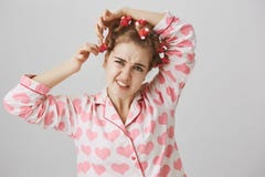 Красота требует поддачи Молодая girly девушка в милых pyjamas принимая дискомфорт волос-curlers, хмуриться и чувствовать или стоковое изображение rf Красота требует поддачи Молодая girly девушка в милых pyjamas принимая дискомфорт волос-curlers, хмуриться и чувствовать или стоковое изображение rf