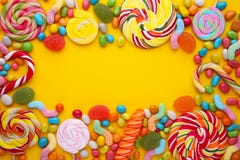 Красочные леденцы на палочке и различная покрашенная круглая конфета на желтой предпосылке стоковая фотография rf Красочные леденцы на палочке и различная покрашенная круглая конфета на желтой предпосылке стоковая фотография rf