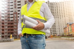 Крупный план архитектора в жилете безопасности представляя с светокопиями на ne стоковое изображение Крупный план архитектора в жилете безопасности представляя с светокопиями на ne стоковое изображение