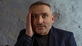 Крутой бизнесмен с серым положением волос и бороды на серой предпосылке стоковое изображение Крутой бизнесмен с серым положением волос и бороды на серой предпосылке стоковое изображение