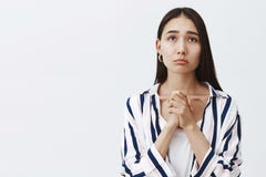 Крытая съемка хмурой милой женщины в striped блузке над футболкой, сжимая руки и морща губы, хмурясь пока gazing стоковое изображение Крытая съемка хмурой милой женщины в striped блузке над футболкой, сжимая руки и морща губы, хмурясь пока gazing стоковое изображение