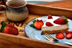 Кусок сырцового белого торта клубники на голубой плите с чашкой кофе здоровая принципиальная схема завтрака стоковые фотографии rf Кусок сырцового белого торта клубники на голубой плите с чашкой кофе здоровая принципиальная схема завтрака стоковые фотографии rf