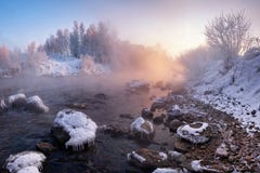 Ландшафт зимы: Река пропуская среди покрытых Снег и покрытых Лед камней и Роза Солнце поднимая над лесом Pinky w стоковая фотография rf Ландшафт зимы: Река пропуская среди покрытых Снег и покрытых Лед камней и Роза Солнце поднимая над лесом Pinky w стоковая фотография rf