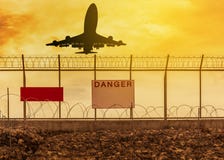 Летание самолета силуэта принимает от взлётно-посадочная дорожка с предпосылкой загородки металла колючей проволоки бритвы безопа Стоковые Фотографии RF Летание самолета силуэта принимает от взлётно-посадочная дорожка с предпосылкой загородки металла колючей проволоки бритвы безопа Стоковые Фотографии RF
