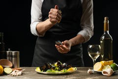 Лимонный сок шеф-повара лить с мидиями с салатом белого вина на темной предпосылке стоковые изображения Лимонный сок шеф-повара лить с мидиями с салатом белого вина на темной предпосылке стоковые изображения