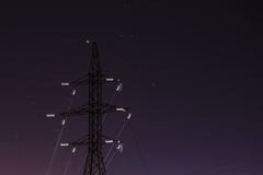 Линии электропередач в освещают контржурным светом луны в небе звезды ночи стоковая фотография rf Линии электропередач в освещают контржурным светом луны в небе звезды ночи стоковая фотография rf