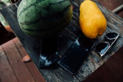 Ложь арбуза и папапайи вся на деревянном столе рядом с телефонами и солнечными очками стоковые изображения rf Ложь арбуза и папапайи вся на деревянном столе рядом с телефонами и солнечными очками стоковые изображения rf