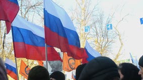 Люди с русскими tricolor флагами и ленты на марше памяти убитого лидера оппозиции Бориса Nemtsov Люди с русскими tricolor флагами и ленты на марше памяти убитого лидера оппозиции Бориса Nemtsov