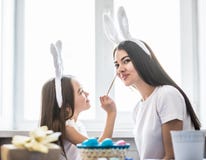 Любящая мать и ее дочь крася белизну пасхальных яя и одина другого имеют потеху Уютная домашняя атмосфера Пасха стоковые изображения rf Любящая мать и ее дочь крася белизну пасхальных яя и одина другого имеют потеху Уютная домашняя атмосфера Пасха стоковые изображения rf