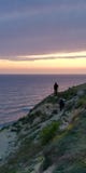 Люди на утесе против ландшафта моря захода солнца Море и небо покрашены в пинке и пурпурных цветах Символическая предпосылка стоковое изображение Люди на утесе против ландшафта моря захода солнца Море и небо покрашены в пинке и пурпурных цветах Символическая предпосылка стоковое изображение