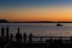 Люди наслаждаясь заходом солнца на пристани моря стоковая фотография rf Люди наслаждаясь заходом солнца на пристани моря стоковая фотография rf