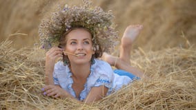 Маленькая девочка в венке отдыхая в стоге сена соломы Маленькая девочка в венке отдыхая в стоге сена соломы