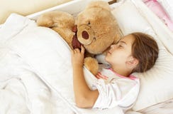 Маленькая девушка брюнет спать в кровати с плюшевым медвежонком стоковые изображения Маленькая девушка брюнет спать в кровати с плюшевым медвежонком стоковые изображения