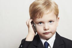 Мальчик в деловом костюме с сотовым телефоном. красивый ребенок. модный ребенк стоковая фотография rf Мальчик в деловом костюме с сотовым телефоном. красивый ребенок. модный ребенк стоковая фотография rf