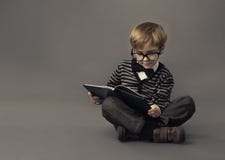 Мальчик в книге чтения стекел, умном st маленького ребенка стоковое изображение rf Мальчик в книге чтения стекел, умном st маленького ребенка стоковое изображение rf