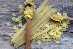 Макаронные изделия квадрата сухие желтые в смешивании с длинными спагетти на и около деревянных ложках стоковые изображения rf Макаронные изделия квадрата сухие желтые в смешивании с длинными спагетти на и около деревянных ложках стоковые изображения rf