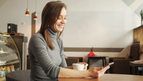 Маленькая девочка в кафе печатает сообщение по телефону и выпивает чашку кофе стоковое изображение Маленькая девочка в кафе печатает сообщение по телефону и выпивает чашку кофе стоковое изображение
