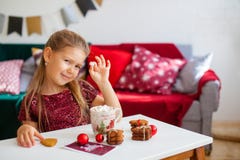 Маленькая девочка в красном платье есть печенья с какао в чашке, красные украшения рождества Chirstmas вокруг стоковая фотография rf Маленькая девочка в красном платье есть печенья с какао в чашке, красные украшения рождества Chirstmas вокруг стоковая фотография rf