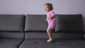 Маленькая девочка с курчавыми светлыми волосами скачет на софу голубые одежды чувствует счастливой движение медленное сток-видео Маленькая девочка с курчавыми светлыми волосами скачет на софу голубые одежды чувствует счастливой движение медленное сток-видео