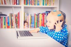 Маленькая девочка с наушниками и компьтер-книжкой стоковое изображение rf Маленькая девочка с наушниками и компьтер-книжкой стоковое изображение rf