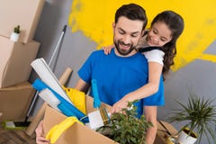 Маленькая дочь с paintbrush обнимает отца, который держит коробку инструментов и вещей стоковые фотографии rf Маленькая дочь с paintbrush обнимает отца, который держит коробку инструментов и вещей стоковые фотографии rf