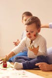 2 маленьких брать с красками на их сторонах одетых в домашних одеждах сидят на деревянном поле в комнате стоковое изображение 2 маленьких брать с красками на их сторонах одетых в домашних одеждах сидят на деревянном поле в комнате стоковое изображение