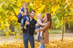 2 малых дет, мальчик и девушка сидят в их руках ` родителей в парке осени стоковая фотография rf 2 малых дет, мальчик и девушка сидят в их руках ` родителей в парке осени стоковая фотография rf
