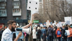Мальчик бежит на ралли с громкоговорителем в руке Клекоты громко в замедленном движении Мальчик бежит на ралли с громкоговорителем в руке Клекоты громко в замедленном движении