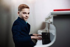 Мальчик играет рояль Стильный ребенок учит сыграть музыкальный инструмент стоковое изображение rf Мальчик играет рояль Стильный ребенок учит сыграть музыкальный инструмент стоковое изображение rf