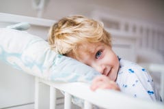 Мальчик малыша стоя в кроватке в спальне дома стоковые изображения Мальчик малыша стоя в кроватке в спальне дома стоковые изображения