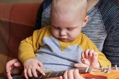 Мама учит, что ее маленький сын играет гитару Предыдущее развитие ребенка стоковое фото rf Мама учит, что ее маленький сын играет гитару Предыдущее развитие ребенка стоковое фото rf