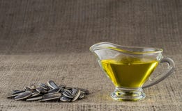 Масло семян подсолнуха в стеклянной шлюпке подливки и пригорошня семян подсолнуха Стоковая Фотография RF Масло семян подсолнуха в стеклянной шлюпке подливки и пригорошня семян подсолнуха Стоковая Фотография RF