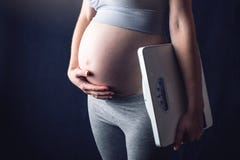 Масштабы удерживания беременной женщины и весят держать одну руку на животе Концепция потери и управления веса во время беременно стоковое фото Масштабы удерживания беременной женщины и весят держать одну руку на животе Концепция потери и управления веса во время беременно стоковое фото