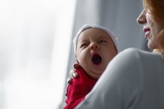 Мать держа милый newborn ребенка в ее оружиях Сонный младенец зевая стоковые изображения rf Мать держа милый newborn ребенка в ее оружиях Сонный младенец зевая стоковые изображения rf