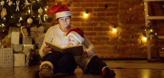 Мать или бабушка при ее маленькие сын или внук читая волшебную книгу в уютной живущей комнате стоковые фотографии rf Мать или бабушка при ее маленькие сын или внук читая волшебную книгу в уютной живущей комнате стоковые фотографии rf