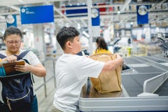 Мать оплатила на счетчике оплатить в торговом центре с сыном держа сумку ткани стоковое изображение Мать оплатила на счетчике оплатить в торговом центре с сыном держа сумку ткани стоковое изображение