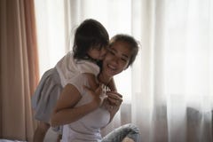 Мать портрета и ее дочь обнимая на спальне стоковые фотографии rf Мать портрета и ее дочь обнимая на спальне стоковые фотографии rf