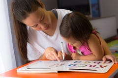 Мать уча ее ребенку как написать алфавиты Концепция Homeschooling Дети фокусируя и концентрируя стоковая фотография rf Мать уча ее ребенку как написать алфавиты Концепция Homeschooling Дети фокусируя и концентрируя стоковая фотография rf