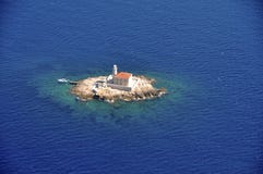 Маяк на малом утесе окруженном с морем сверху стоковое фото Маяк на малом утесе окруженном с морем сверху стоковое фото