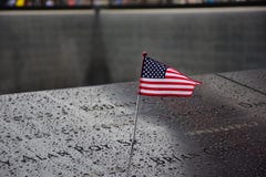 Мемориал на эпицентре Манхаттане для теракта 11-ое сентября при американский флаг стоя около имен жертв Engra стоковые фотографии rf Мемориал на эпицентре Манхаттане для теракта 11-ое сентября при американский флаг стоя около имен жертв Engra стоковые фотографии rf