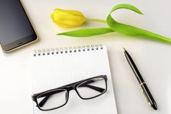 Место для работы на таблице тюльпан, тетрадь, стекла, smartphone и ручка Стоковое Изображение Место для работы на таблице тюльпан, тетрадь, стекла, smartphone и ручка Стоковое Изображение