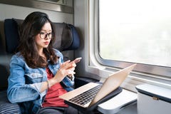 Милая азиатская женщина используя smartphone и компьтер-книжку на поезде, космос экземпляра на концепции окна, деловых поездок ил Стоковые Изображения Милая азиатская женщина используя smartphone и компьтер-книжку на поезде, космос экземпляра на концепции окна, деловых поездок ил Стоковые Изображения