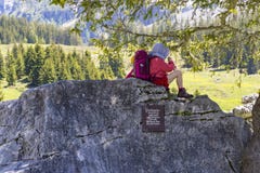 Милый ребенк отдыхая на большом утесе около озера Oeschinensee в Bernese Oberland, Швейцарии стоковая фотография rf Милый ребенк отдыхая на большом утесе около озера Oeschinensee в Bernese Oberland, Швейцарии стоковая фотография rf