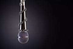 Микрофон с цепью, показывающ идею свободы печати или свободы выражения на темной предпосылке Мировая пресса стоковая фотография rf Микрофон с цепью, показывающ идею свободы печати или свободы выражения на темной предпосылке Мировая пресса стоковая фотография rf