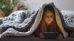 Милая девушка лежа под одеялом с сенсорной панелью видеоматериал Милая девушка лежа под одеялом с сенсорной панелью видеоматериал