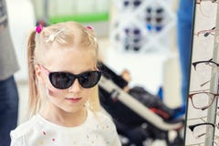 Милая маленькая молодая кавказская белокурая девушка пробуя дальше и выбирая солнечные очки перед зеркалом в оптическом магазине стоковое изображение Милая маленькая молодая кавказская белокурая девушка пробуя дальше и выбирая солнечные очки перед зеркалом в оптическом магазине стоковое изображение