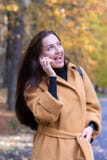 Милая молодая женщина идя в парк осени говоря на падении листьев телефона передвижном ослабляет стоковая фотография Милая молодая женщина идя в парк осени говоря на падении листьев телефона передвижном ослабляет стоковая фотография